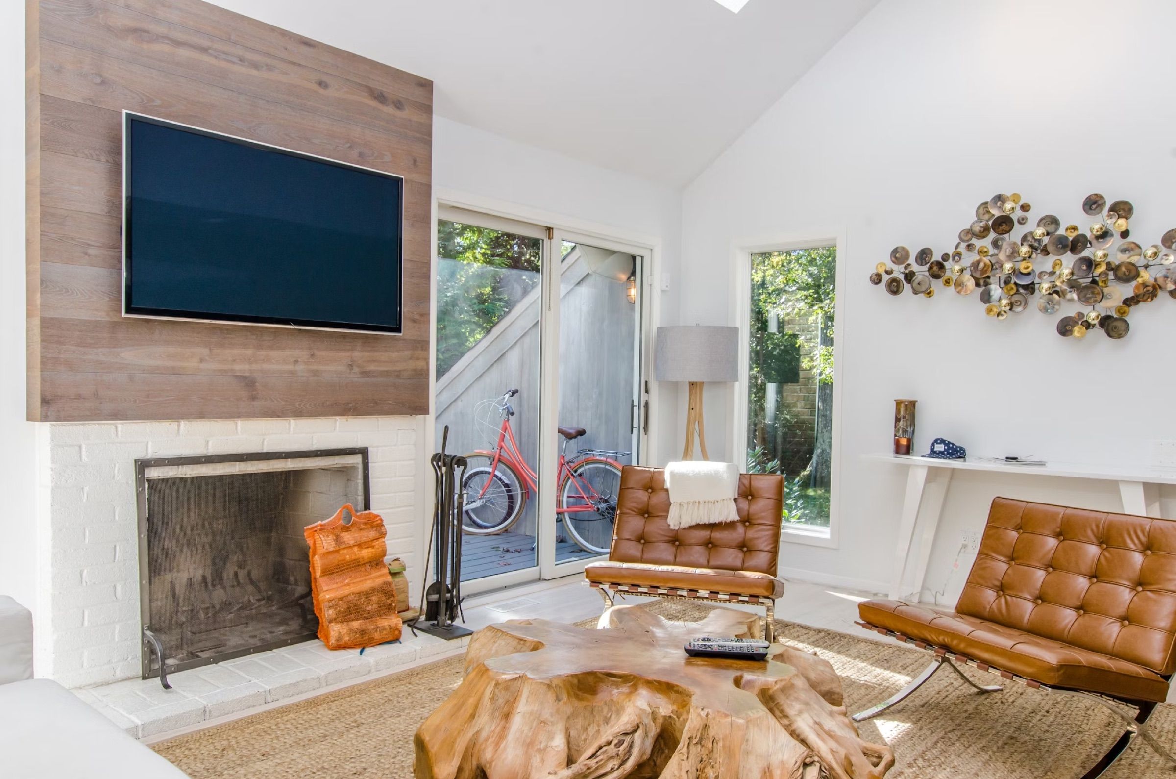 Bright living room with a fireplace, tan leather chairs and a large wooden coffee table