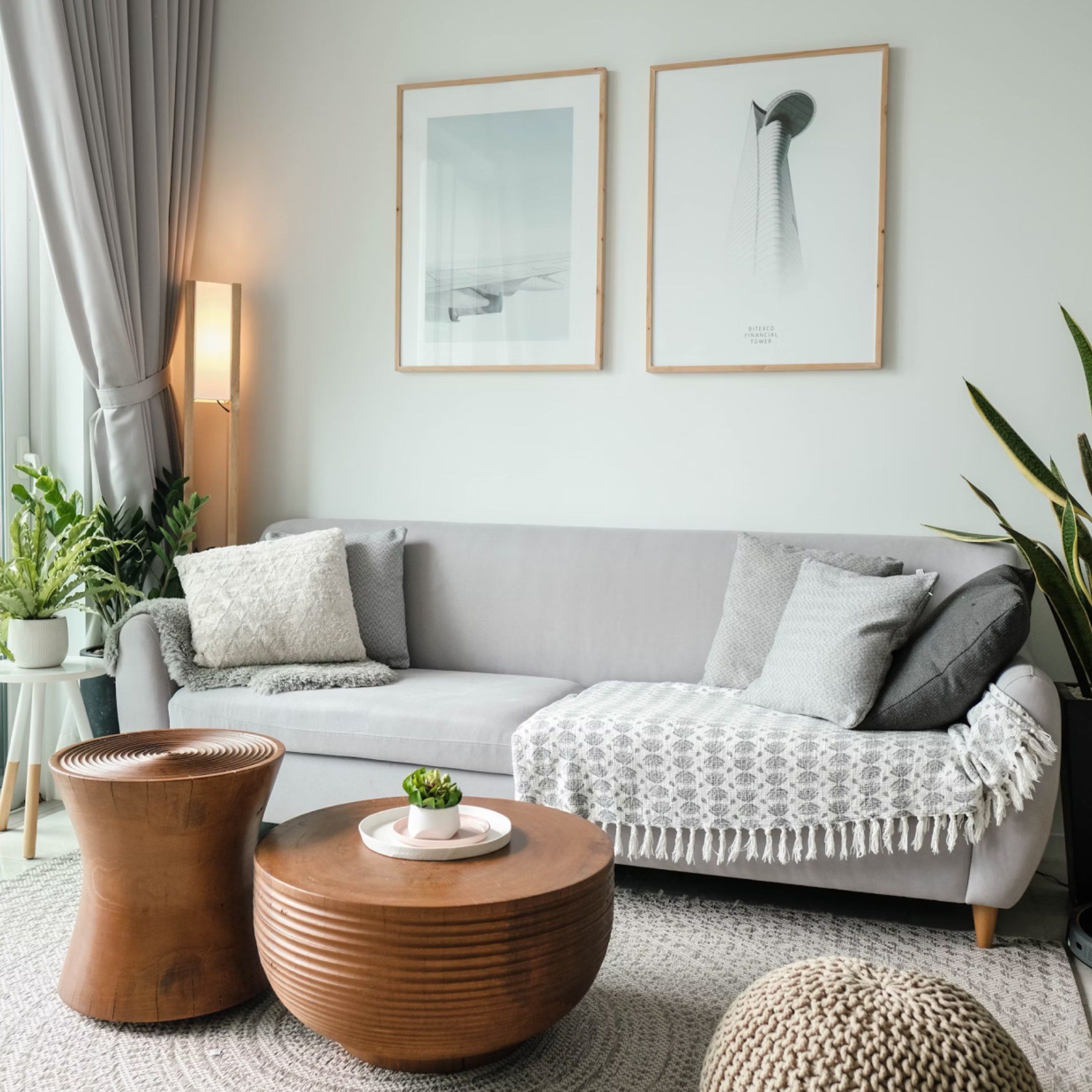 A bright living room with a grey sofa, a wooden coffee table and two framed prints