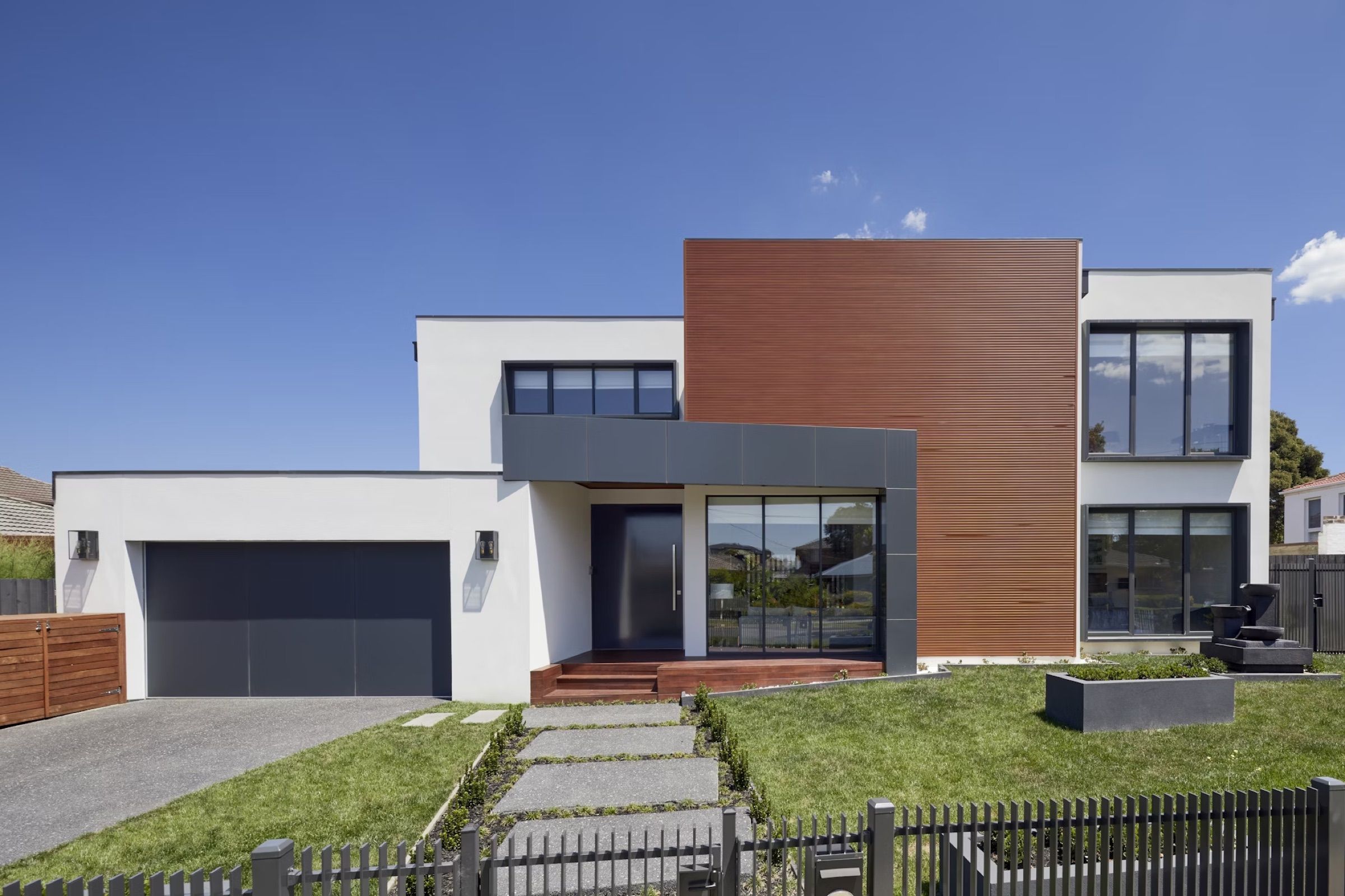 Modern detached house with a timber-clad section and front lawn