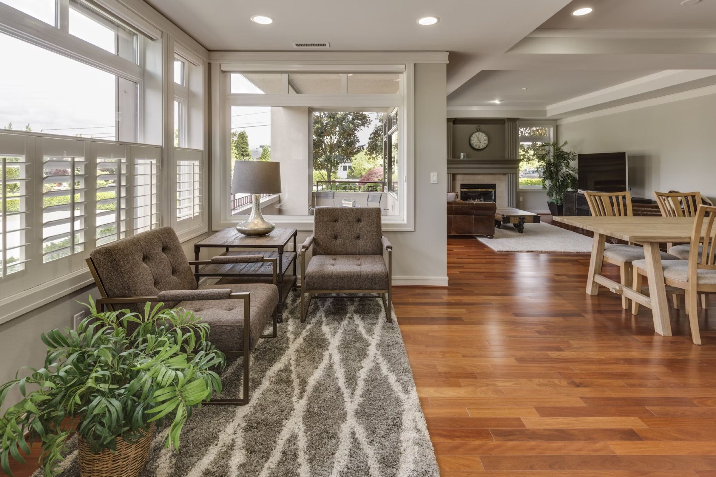 Sunroom living area with shutters, armchairs, a rug and wooden floors