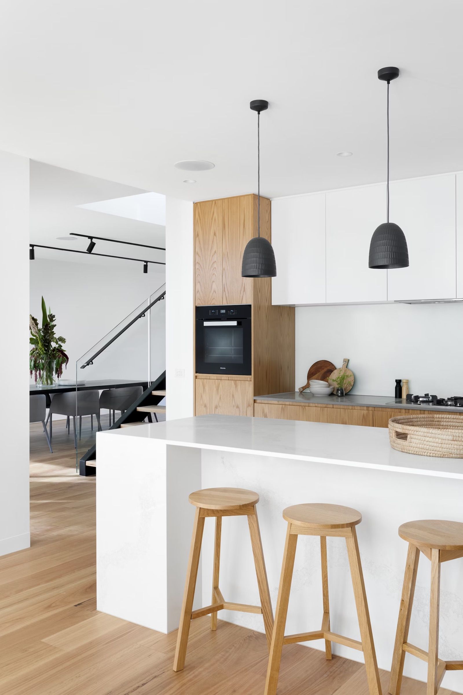 White kitchen with breakfast bar, pendant lights and wooden stools